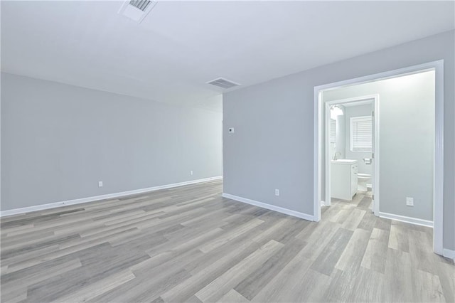 spare room featuring visible vents, light wood-type flooring, and baseboards