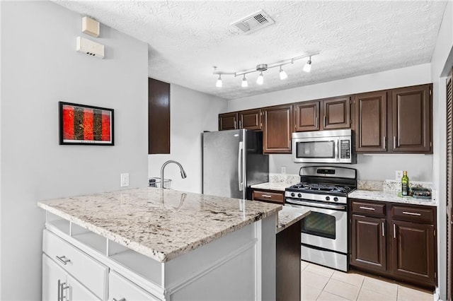 kitchen featuring visible vents, dark brown cabinets, light tile patterned floors, a peninsula, and stainless steel appliances