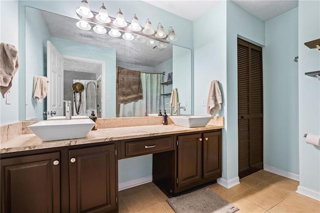 full bathroom featuring tile patterned flooring, tiled shower, and a sink