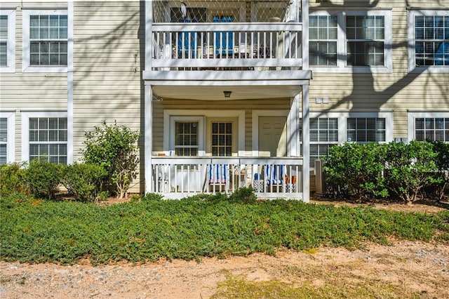 view of exterior entry with covered porch and a balcony