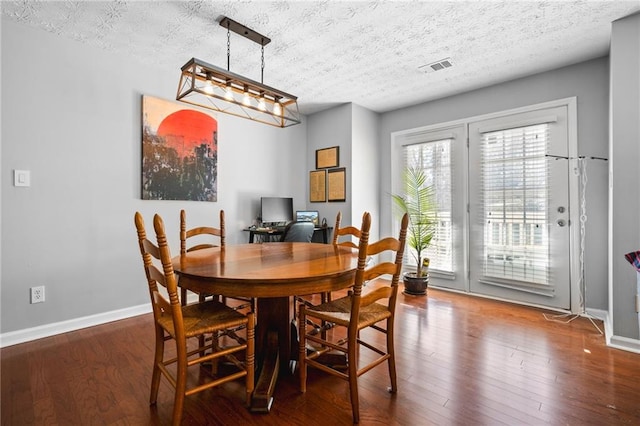 dining room featuring visible vents, wood finished floors, baseboards, and a textured ceiling