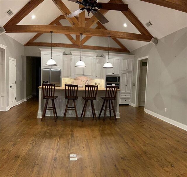 kitchen featuring a spacious island, stainless steel appliances, pendant lighting, a breakfast bar area, and dark hardwood / wood-style floors