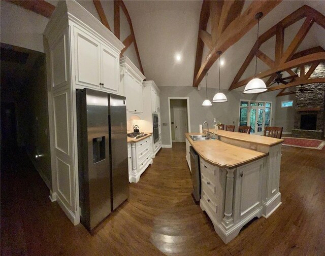 kitchen featuring an island with sink, appliances with stainless steel finishes, white cabinetry, decorative light fixtures, and sink