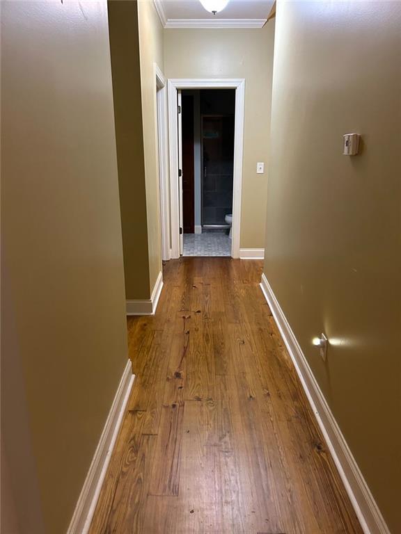 corridor with ornamental molding and hardwood / wood-style floors