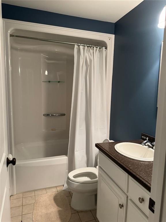 full bathroom with toilet, shower / tub combo with curtain, vanity, and tile patterned flooring