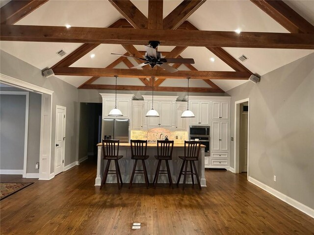 kitchen featuring appliances with stainless steel finishes, a spacious island, backsplash, dark hardwood / wood-style flooring, and a kitchen breakfast bar