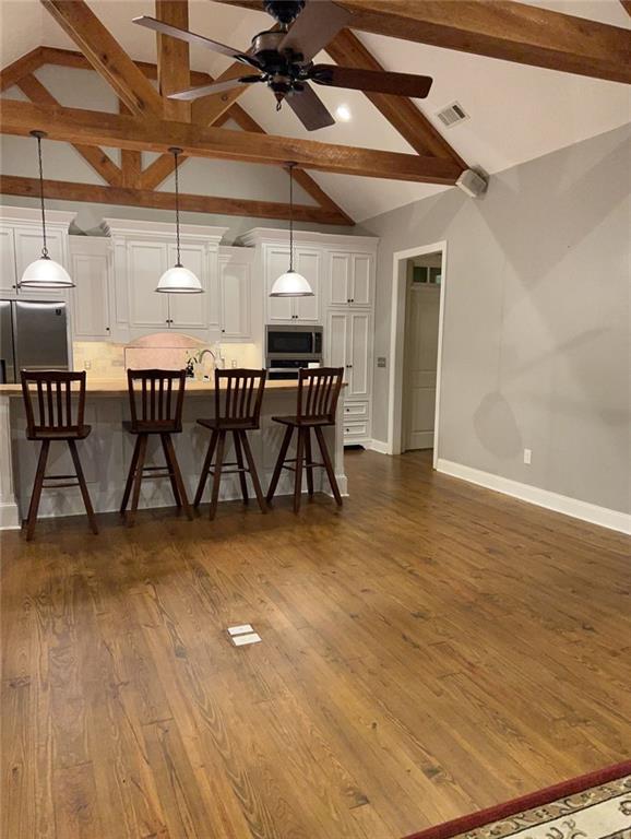 dining room featuring beam ceiling, high vaulted ceiling, dark wood-type flooring, and ceiling fan