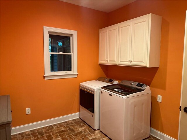 clothes washing area with washer and dryer and cabinets