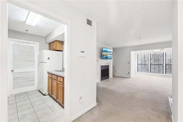 kitchen featuring a fireplace, light carpet, and white fridge