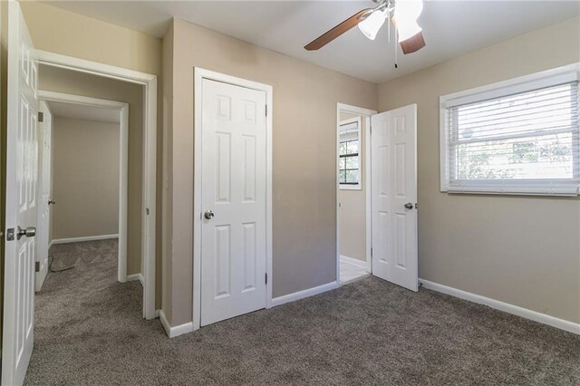 unfurnished bedroom featuring ceiling fan, dark carpet, and a closet