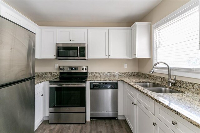 kitchen with light stone countertops, appliances with stainless steel finishes, sink, dark hardwood / wood-style floors, and white cabinetry