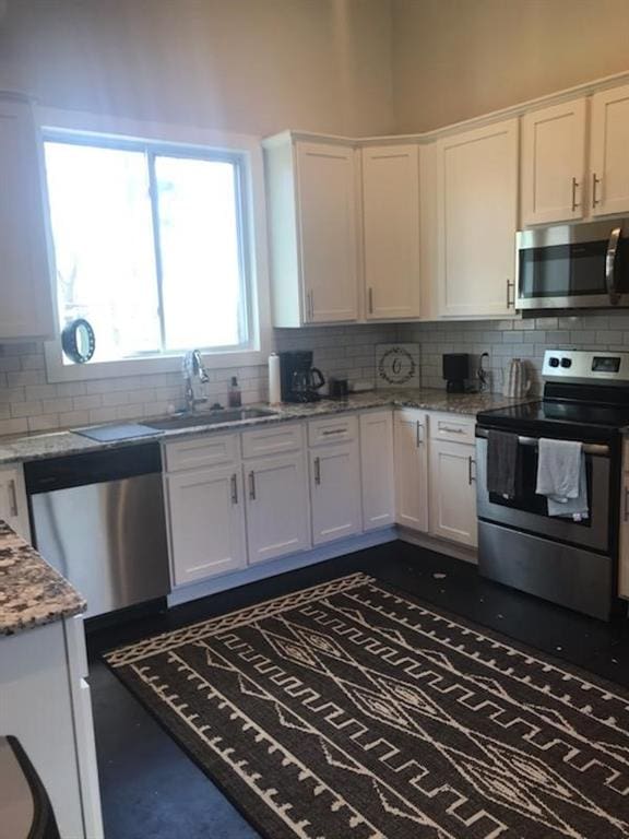 8669 Davis St, Braselton, GA 30517 - kitchen featuring stainless steel appliances, a sink, white cabinetry, decorative backsplash, and light stone countertops