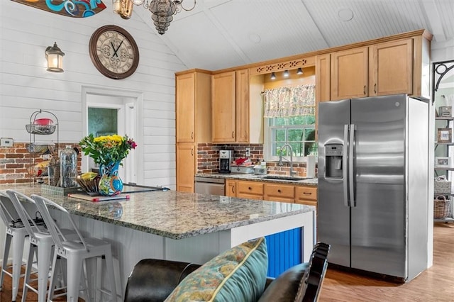 8669 Davis St, Braselton, GA 30517 - kitchen featuring appliances with stainless steel finishes, a sink, vaulted ceiling, light wood finished floors, and a breakfast bar