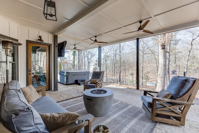 view of patio featuring ceiling fan, an outdoor living space with a fire pit, and a hot tub