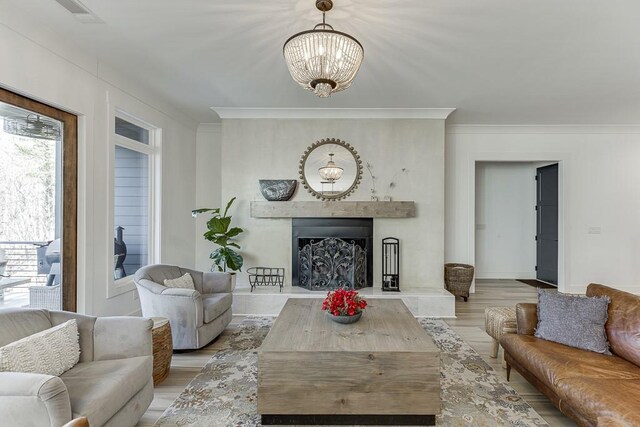 living room with light hardwood / wood-style floors, ornamental molding, and a notable chandelier