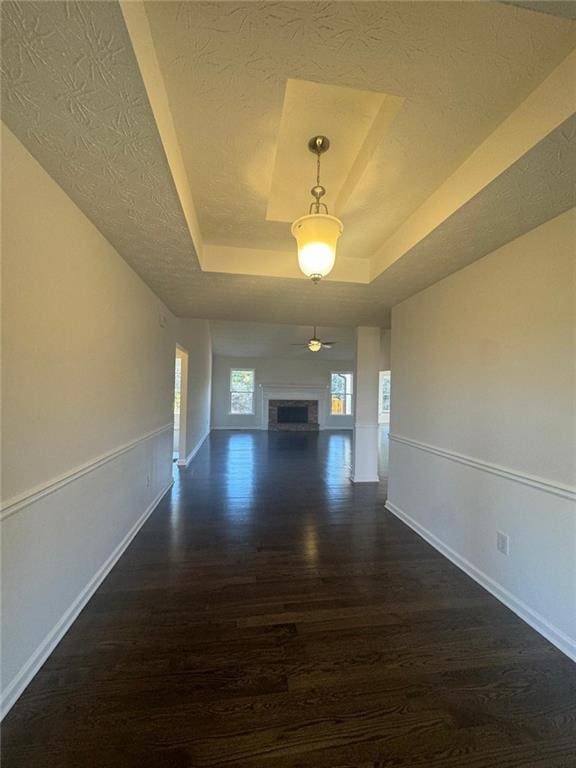 hallway with dark hardwood / wood-style flooring, a raised ceiling, and a textured ceiling