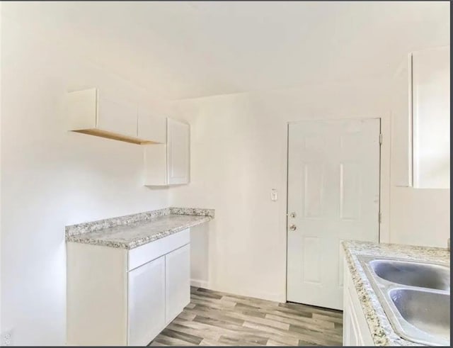 kitchen featuring light countertops, white cabinets, light wood-style floors, and a sink