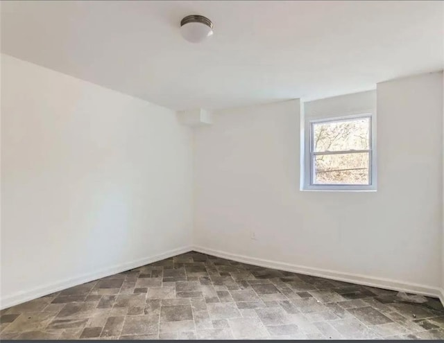 spare room featuring baseboards and stone finish floor