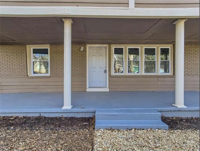 property entrance with brick siding and a porch