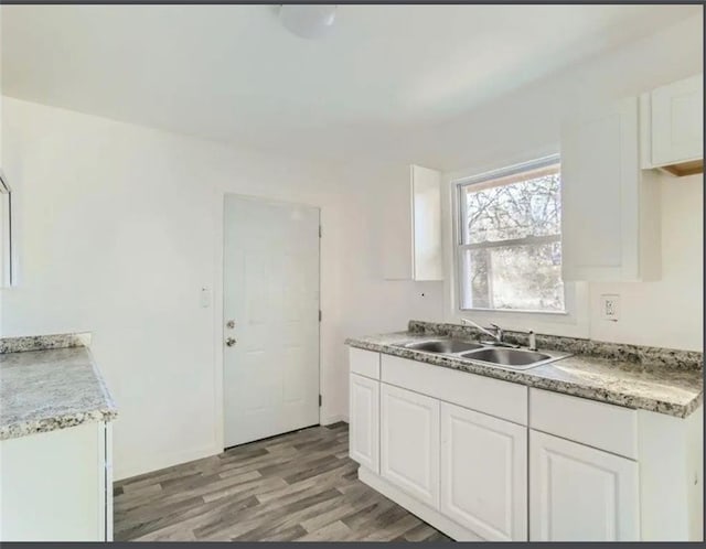 kitchen with light countertops, white cabinets, light wood-style floors, and a sink