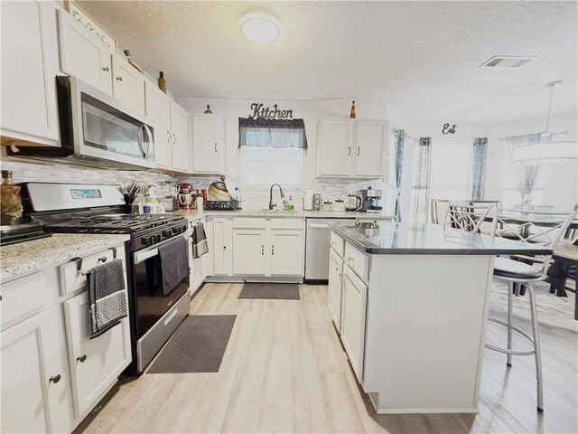 kitchen featuring appliances with stainless steel finishes, visible vents, a kitchen island, and white cabinetry