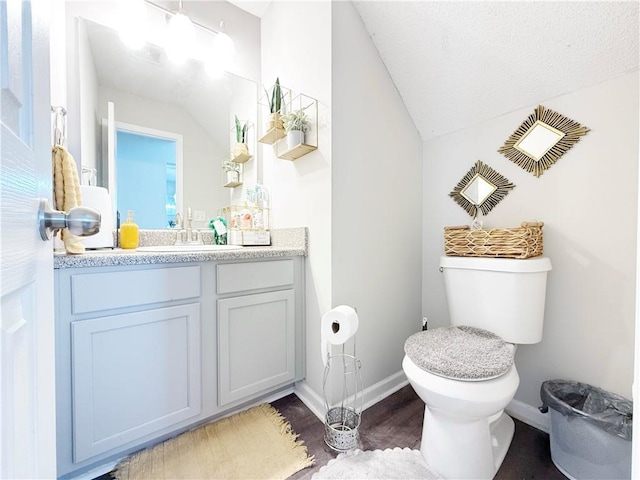 bathroom with lofted ceiling, wood finished floors, vanity, and toilet