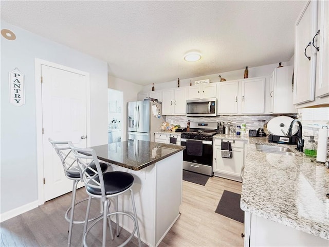 kitchen with appliances with stainless steel finishes, light wood-style floors, a sink, and a breakfast bar