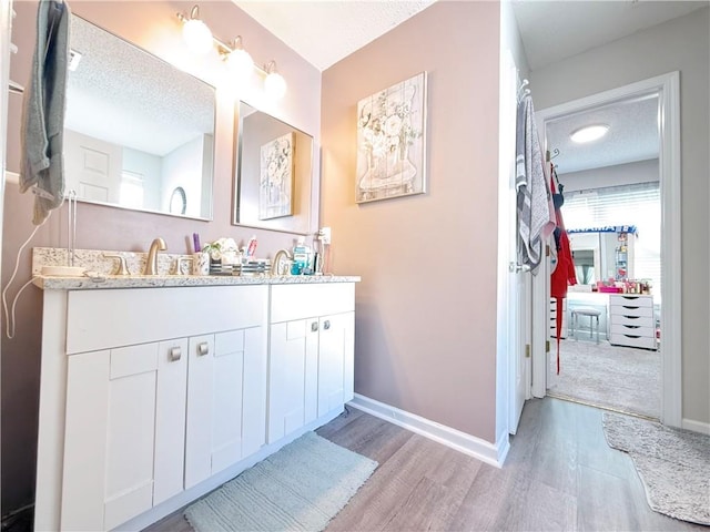 full bathroom with a textured ceiling, baseboards, and wood finished floors