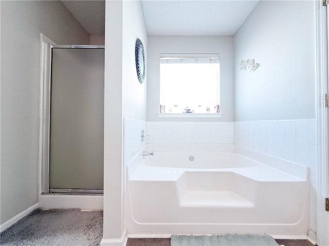 full bath featuring a stall shower, a bath, and baseboards