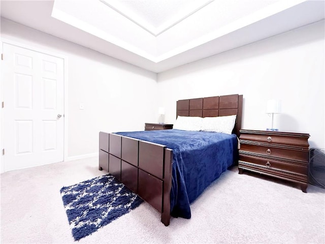 bedroom with a tray ceiling, carpet flooring, and baseboards