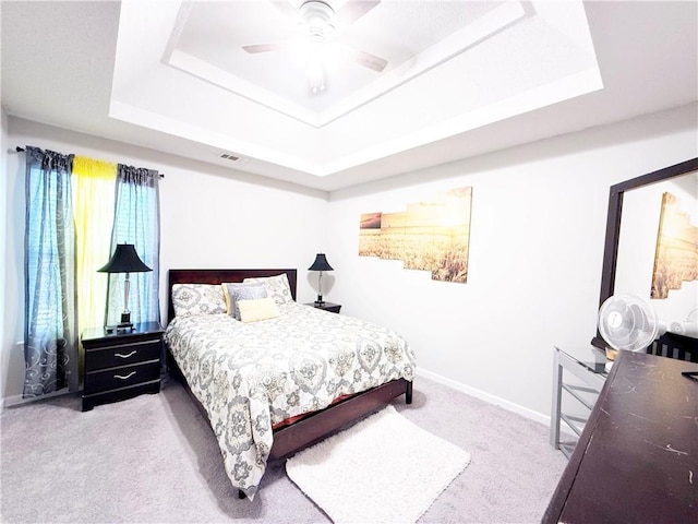 bedroom with carpet flooring, a raised ceiling, visible vents, and baseboards