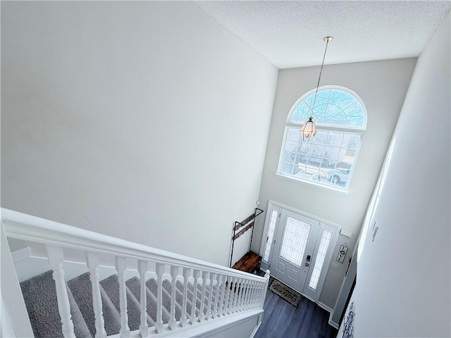 foyer with a textured ceiling, dark wood-type flooring, stairway, and a high ceiling