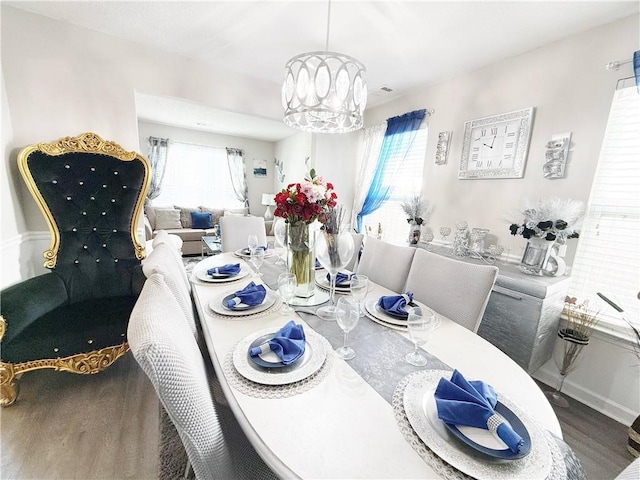 dining space featuring baseboards, plenty of natural light, an inviting chandelier, and wood finished floors