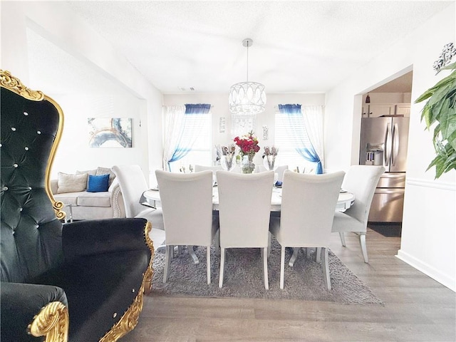 dining space featuring wood finished floors, visible vents, and an inviting chandelier