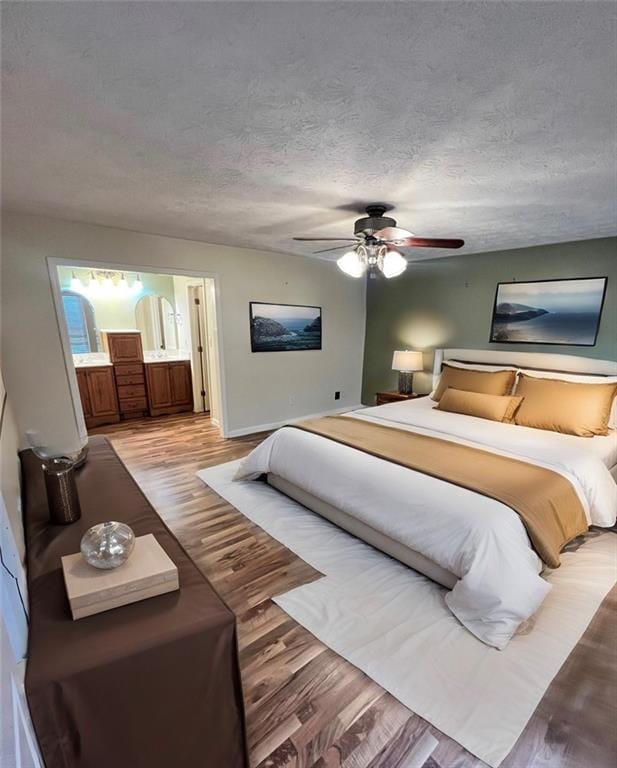 bedroom with ceiling fan, connected bathroom, a textured ceiling, and light hardwood / wood-style flooring