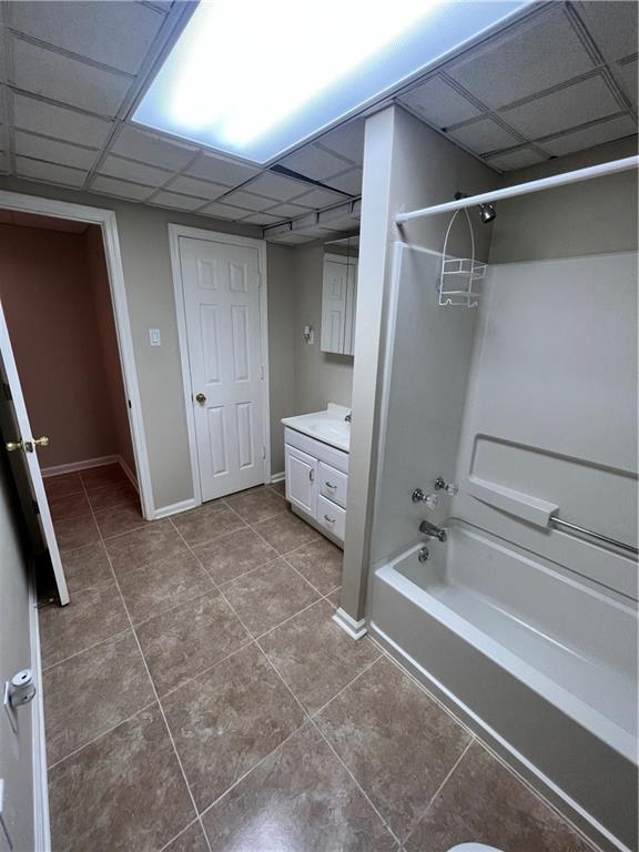 bathroom featuring a drop ceiling, vanity, tile patterned floors, and shower / bath combination