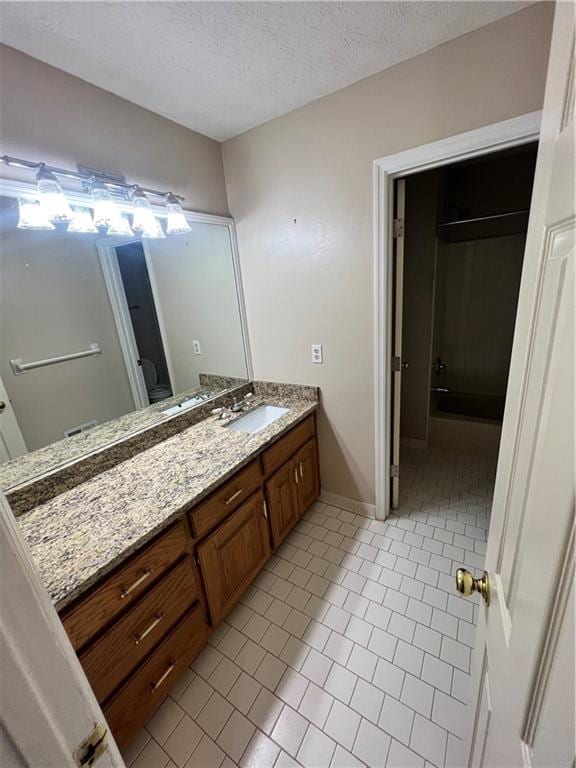 bathroom with vanity, a textured ceiling, and tile patterned flooring