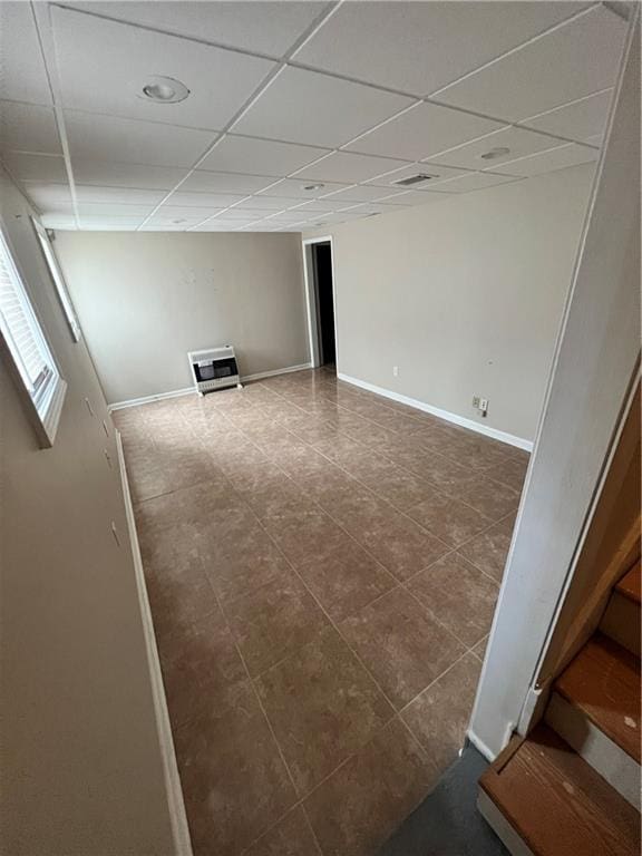 tiled empty room featuring a paneled ceiling and heating unit