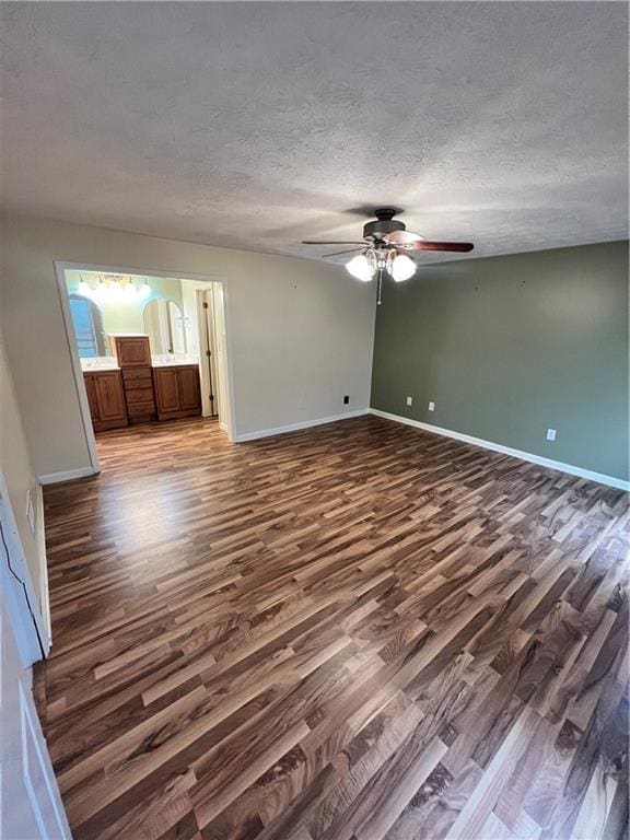 unfurnished room with a textured ceiling, dark wood-type flooring, and ceiling fan