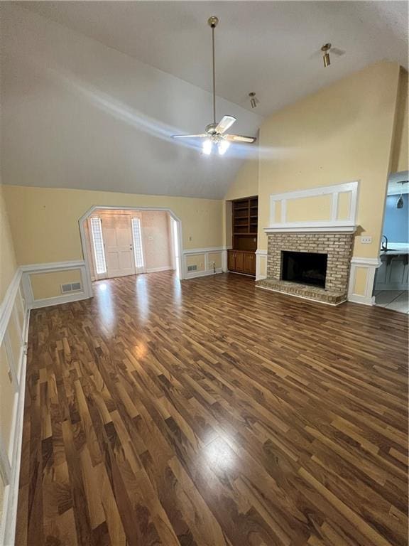 unfurnished living room with lofted ceiling, ceiling fan, dark wood-type flooring, and a fireplace