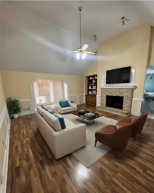 living room featuring vaulted ceiling, dark hardwood / wood-style floors, built in shelves, a brick fireplace, and ceiling fan