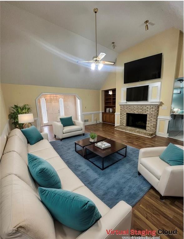 living room featuring lofted ceiling, hardwood / wood-style floors, ceiling fan, and a brick fireplace