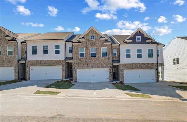 multi unit property featuring driveway, a garage, and brick siding