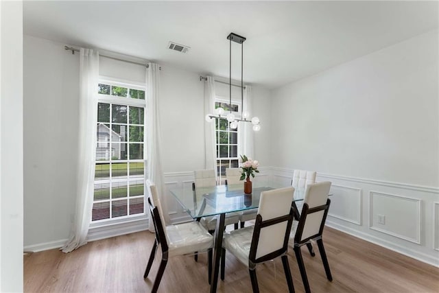 3285 Country Walk Dr, Powder Springs, GA 30127 - dining area featuring wood finished floors, a chandelier, a wainscoted wall, and a decorative wall