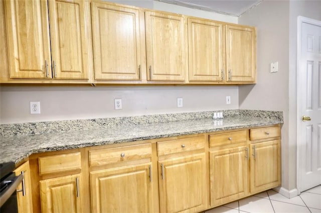 kitchen with light stone counters, light brown cabinetry, range, and light tile patterned floors