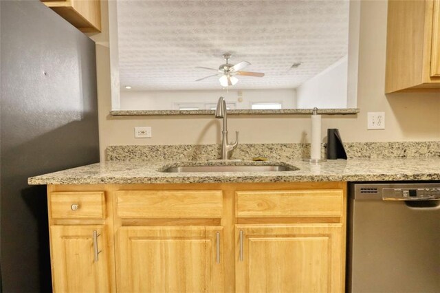 kitchen featuring a sink, a ceiling fan, black dishwasher, light stone countertops, and light brown cabinetry