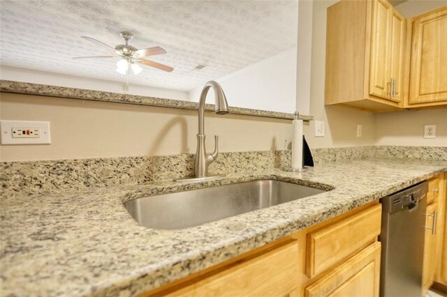 kitchen with a ceiling fan, light brown cabinets, a sink, light stone countertops, and dishwasher