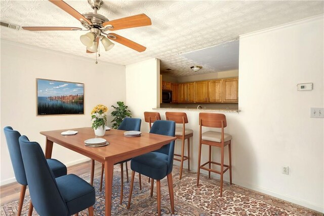 dining area featuring baseboards, visible vents, ceiling fan, and a textured ceiling