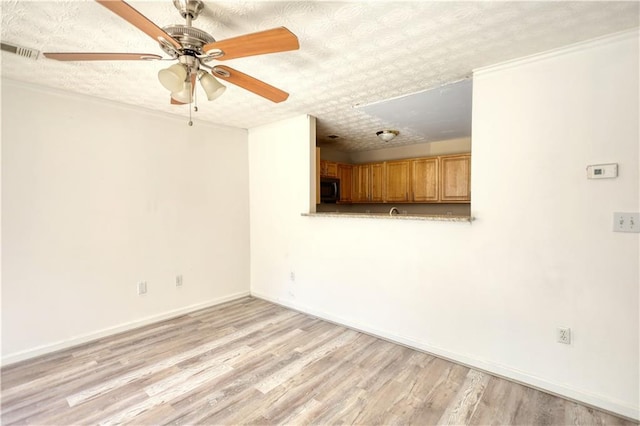 unfurnished living room with light wood-style floors, baseboards, visible vents, and a textured ceiling
