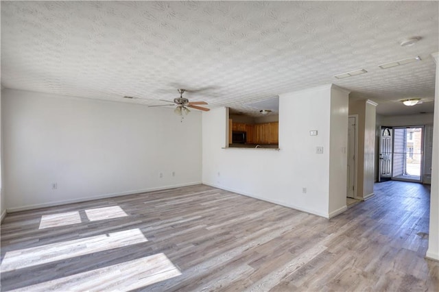 spare room with light wood finished floors, baseboards, and a textured ceiling